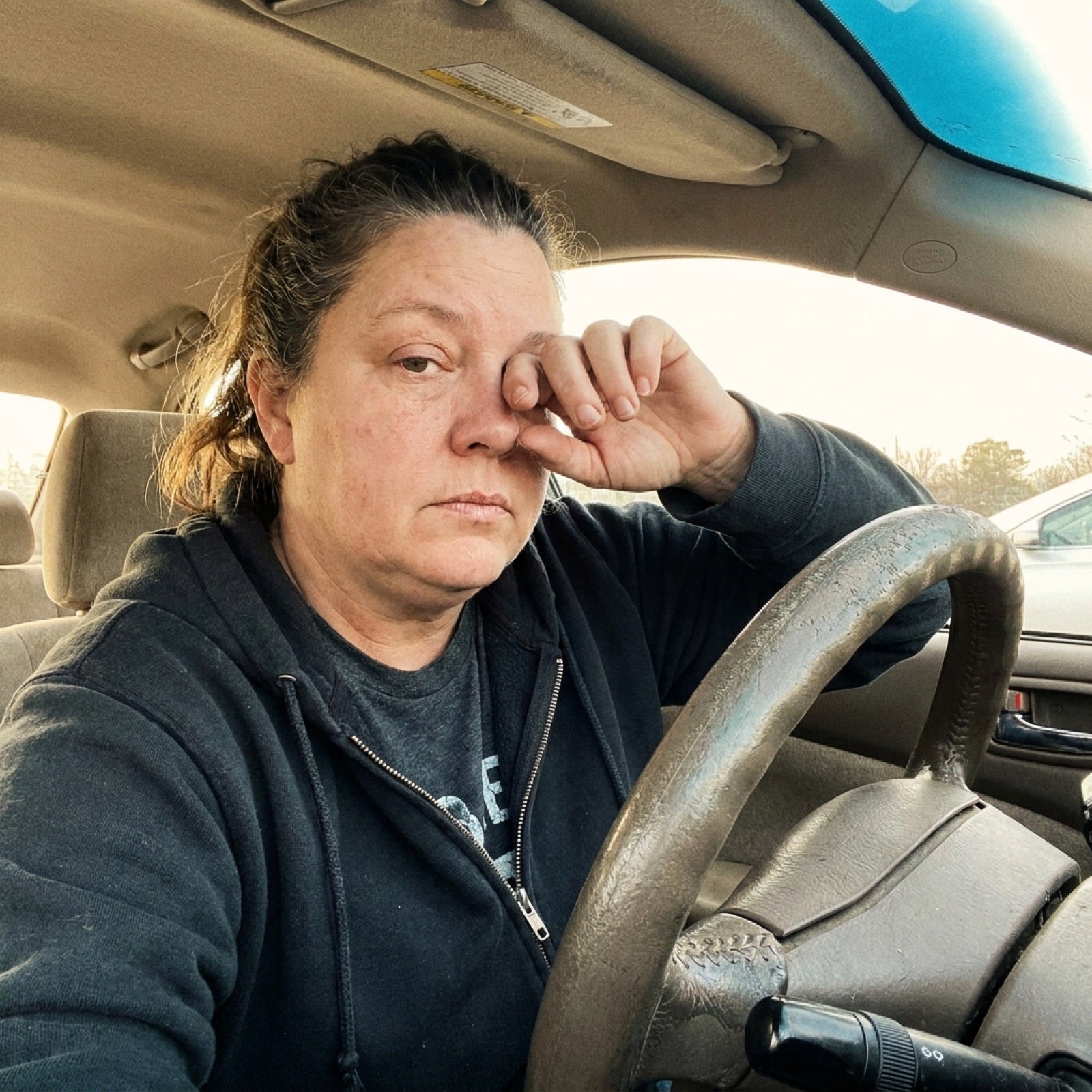 Exhausted woman rubbing her eyes in her car