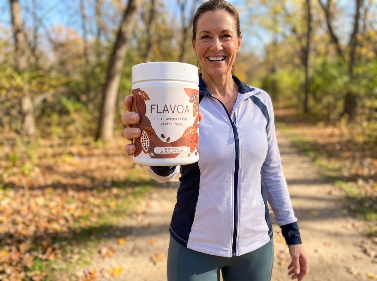 Smiling woman on a walking trail holding up a jar of Flavoa