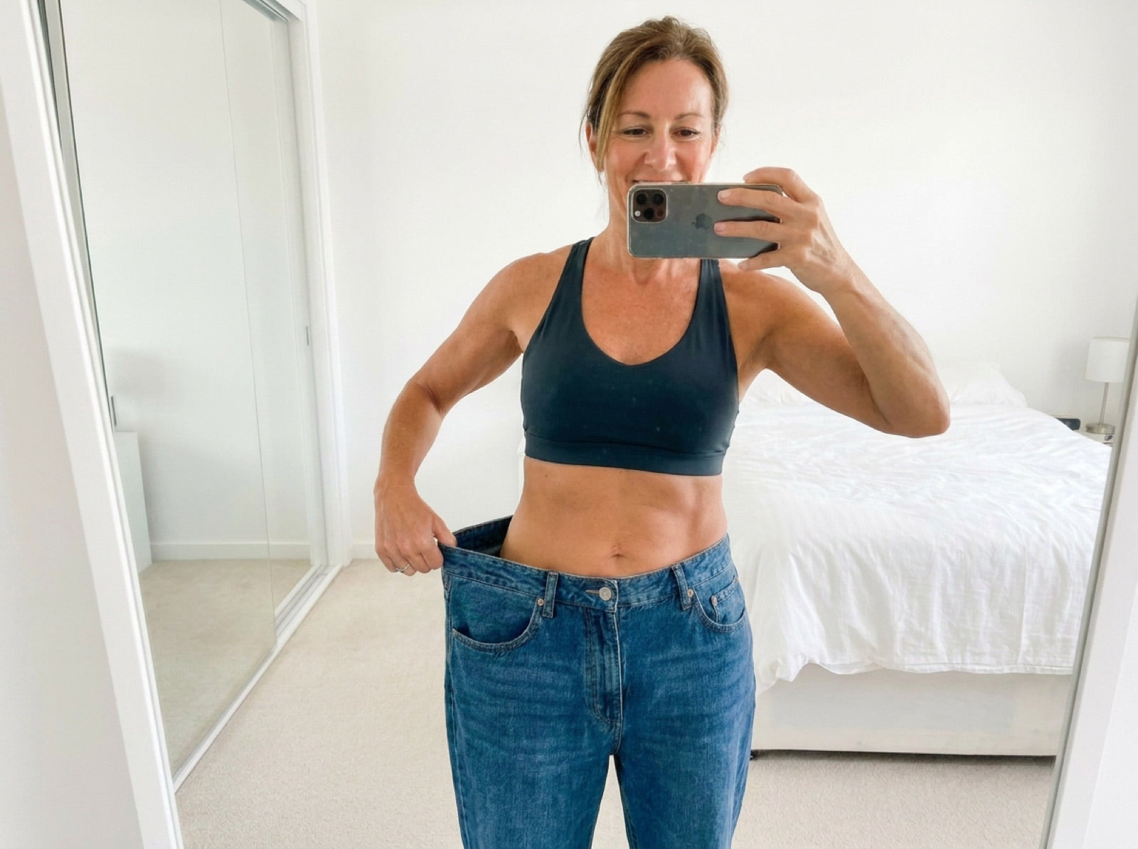 Woman holding out the waistband of her now too-big jeans