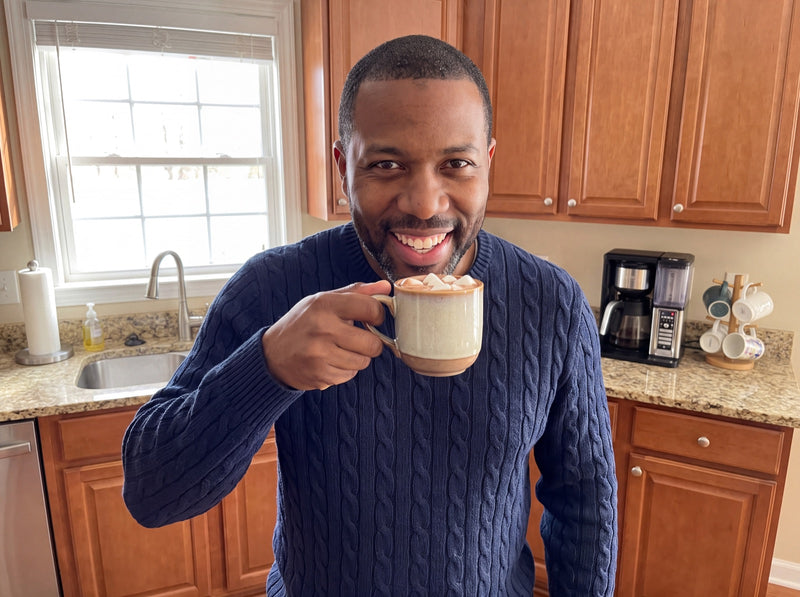 Smiling man enjoying a cup of cocoa in his kitchen